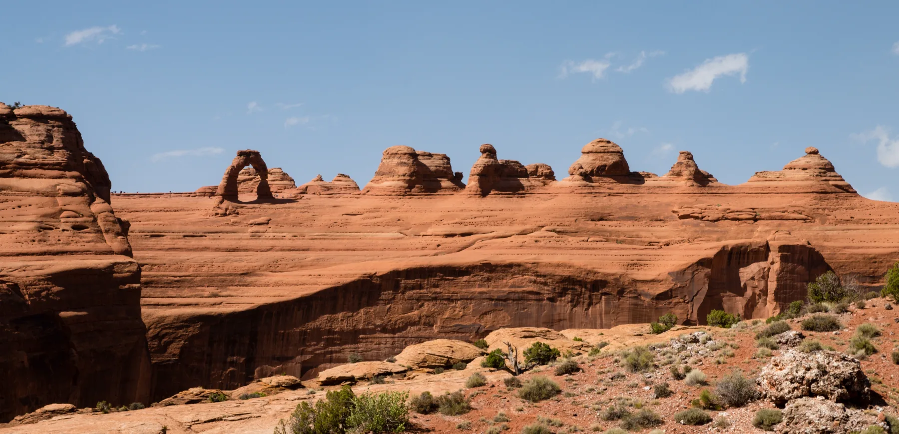 Cliffs, bluffs and natural arches in a wide Arches National Park landscape.
